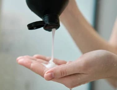 Example photo: a black bottle pouring shampoo into a woman's palm